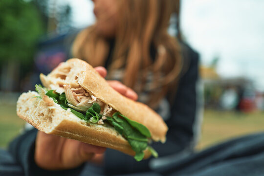 Close-up of a chicken and rocket sandwich on ciabatta held by a child