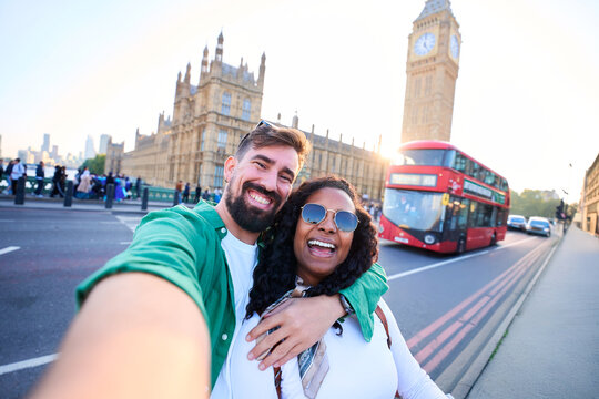 Happy young multiracial couple posing for a selfie in London while visiting the city sights. Copy space.