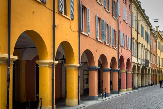 Typical colorful historic buildings in Modena with porticoes along a cobblestone street, Emilia-Romagna, Italy