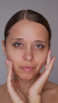 Young woman showing slimmer cheeks and sculpted face after buccal fat removal surgery, demonstrating aesthetic beauty result on gray background