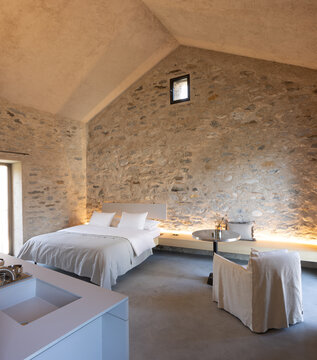 The interior of a beautiful bedroom with a very cosy atmosphere. The walls are made of stone and the room has a romantic feel. The bed is large and sleeps two people. It is a luxury flat.