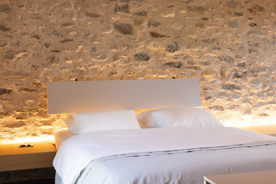 The interior of a beautiful bedroom with a very cosy atmosphere. The walls are made of stone and the room has a romantic feel. The bed is large and sleeps two people. It is a luxury flat.