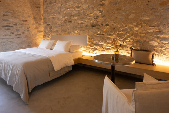 The interior of a beautiful bedroom with a very cosy atmosphere. The walls are made of stone and the room has a romantic feel. The bed is large and sleeps two people. It is a luxury flat.
