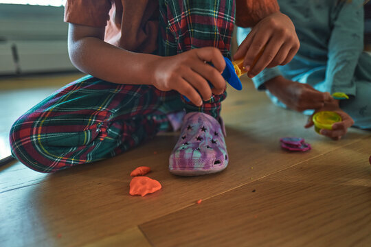 Two children sitting on a wooden floor playing with play dough