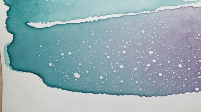 Showing teal-lavender wash developing on textured paper in studio, droplets landing making speckles