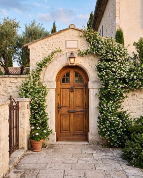 Porte en bois ancienne dans une entr&eacute;e proven&ccedil;ale en pierre, entour&eacute;e de jasmin &eacute;toil&eacute; fleuri, lumi&egrave;re du soir