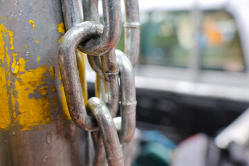 Naklejka premium Worn metal chain metal link steel chain rusty chain painted post yellow paint close up shallow depth of field texture