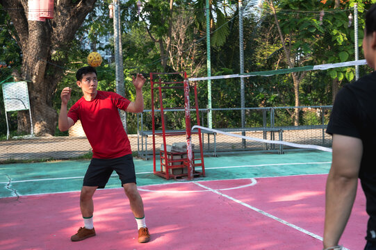 An athletic male Thai sepak takraw player performing a powerful head strike to pass or return the rattan ball during a competitive match on an outdoor court