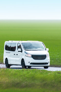 White service van driving beside grassy field