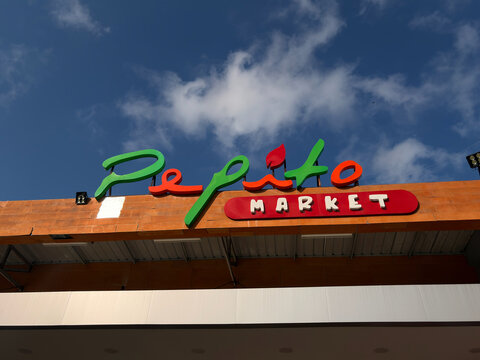 A colorful sign for Pepito Market is displayed against a bright blue sky. The sign features vibrant green and red lettering, drawing attention to the market's name.