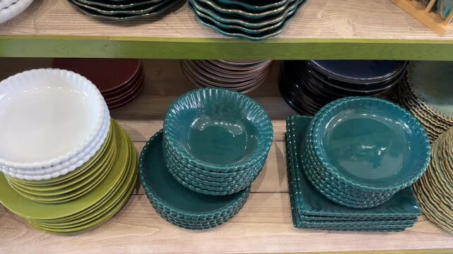 Ceramic plates and bowls with textured patterns displayed on wooden shelves in a kitchenware store
