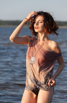 Nude woman standing in water posing outdoors