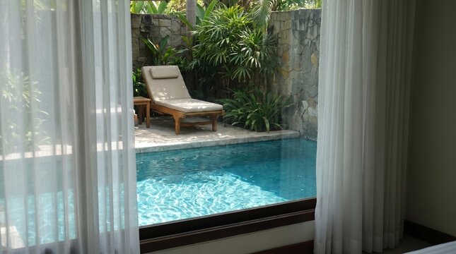 Private villa plunge pool and sun lounger seen through sheer window curtains