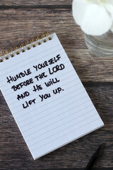 Fototapeta premium Christian quote for humility in a notebook on a wooden background. Biblical concept of repentance, obedience, and faith in God Jesus Christ.