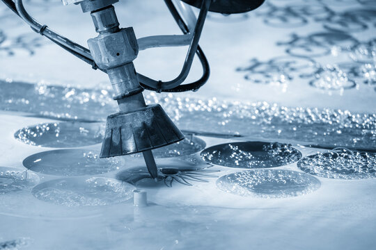 Multi axis abrasive waterjet cutting machine cutting aluminum plate in light blue lighting