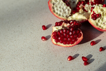 Close-up of ripe pomegranate pieces and seeds scattered on a light textured background in bright natural sunlight. © Yavolha