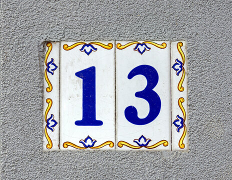 Number 13 on metal plate house address on outdoor facade wall