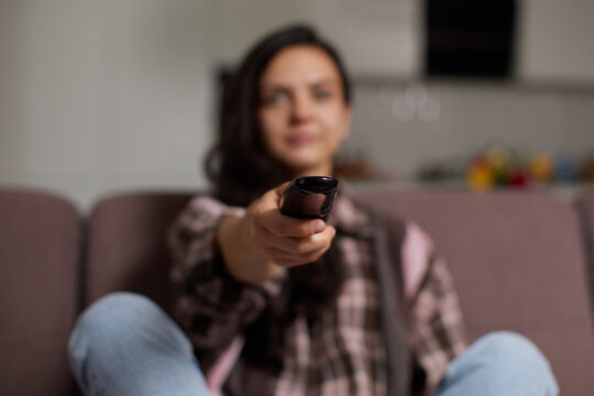 Woman changing tv channel with remote control