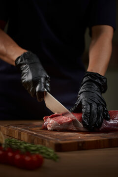 Butcher hands cutting raw beef steak on board