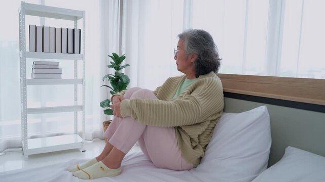 Melancholy Reflection: An elderly woman sits pensively on a bed, gazing wistfully away, her posture and expression conveying a deep sense of introspection and perhaps a touch of solitude.