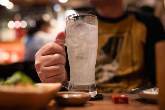 居酒屋で冷たいサワーのジョッキを持つ男性の手元