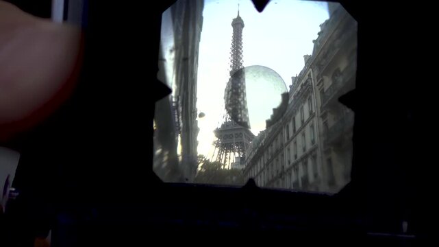 Close-up of a photographer using a vintage film camera to capture the Eiffel Tower in Paris, France.