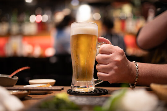 居酒屋で冷えた生ビールを持つ男性の手元