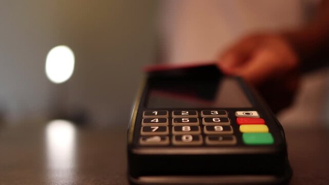 Customer making contactless payment with credit card on a pos terminal at a counter. Electronic pay pass technology concept