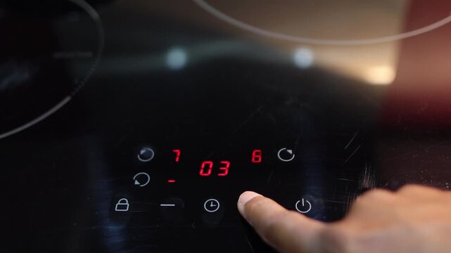 Person programming an induction cooktop with a digital touchscreen display for precise temperature control and cooking time