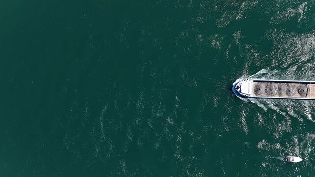 Aerial view of a cargo barge navigating the deep green waters of the Rhine river near Kembs, Grand Est, France.
