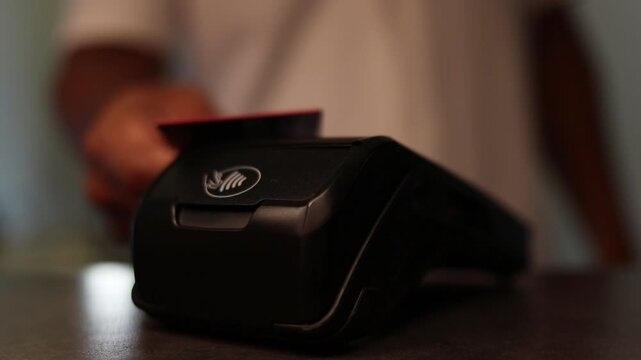 Customer using contactless credit card on a pos terminal for electronic payment at a checkout counter