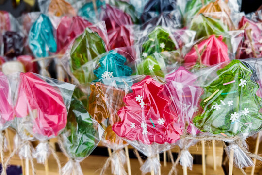 A market stand shows various candy treats shaped like Christmas trees. This display is filled with bright colors and is popular during the holiday season