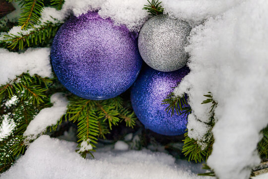 Christmas tree stands adorned with purple and silver ornaments surrounded by fresh snow in a winter landscape