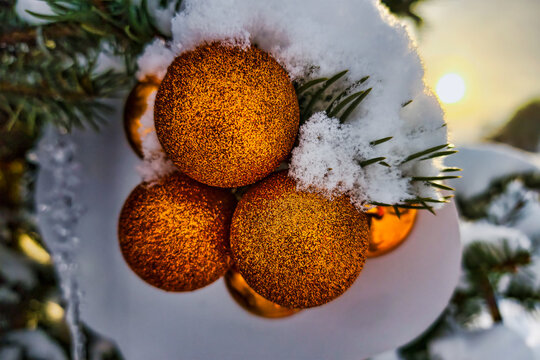 A Christmas tree is covered with snow and has shiny ornaments. It is bright and vivid against the winter sky, bringing a festive look to the cold environment