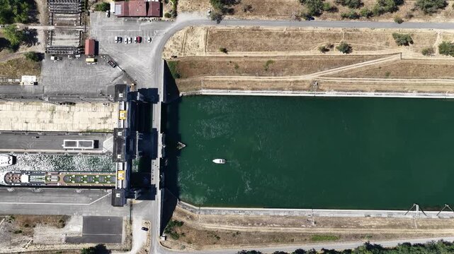 Aerial view of the Kembs lock and dam structure on the Rhine river with a small boat in the water, Kembs, Grand Est, France.