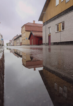 Reflections of wooden houses in a street puddle