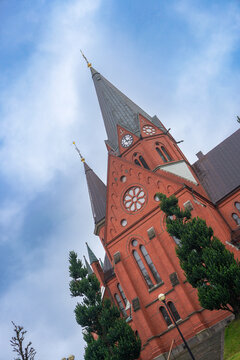 Red brick church tower under cloudy sky