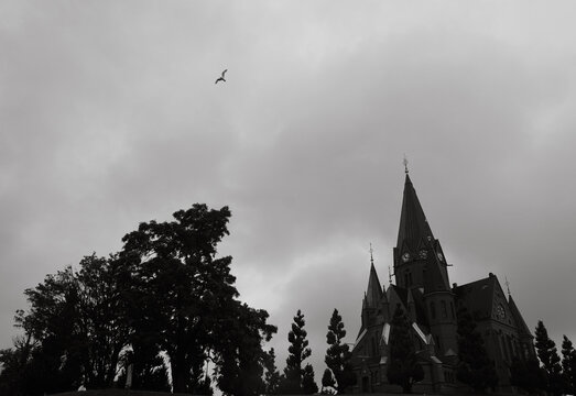 Silhouette of a church and trees under a cloudy sky