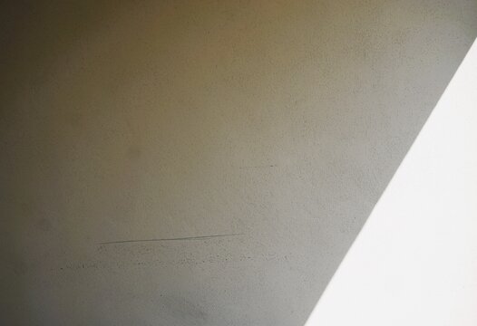 Abstraktes Motiv mit alter wei&szlig;er Betonwand und Licht- und Schattenmuster bei Sonne am Morgen im Sommer als Hintergrund