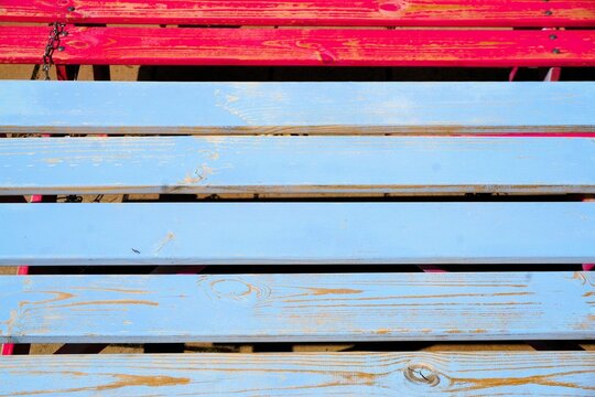 Abstraktes Motiv hellblauer und roter verwitterter Lattenholzfl&auml;che bei Sonne am Morgen im Sommer als Hintergrund