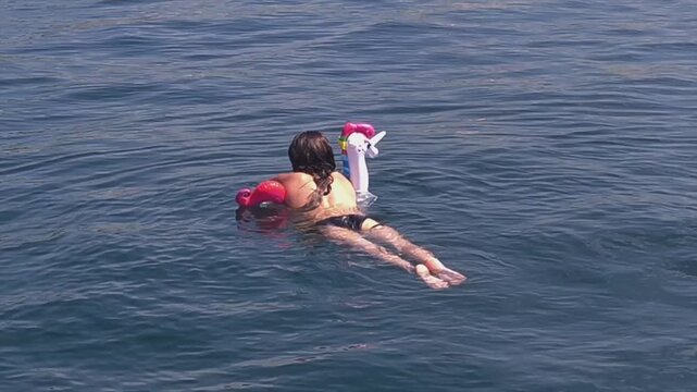 Woman floating on unicorn inflatable ring in calm Mediterranean Sea