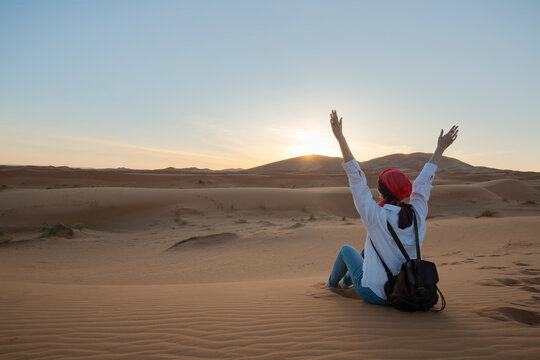 Lonely woman sitting on the sand in the vast desert , contemplating solitude and nature