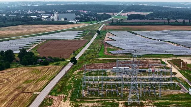 Aerial view of a large solar farm with a power substation surrounded by agricultural fields and forests in Tume, Tukums Municipality, Latvia.