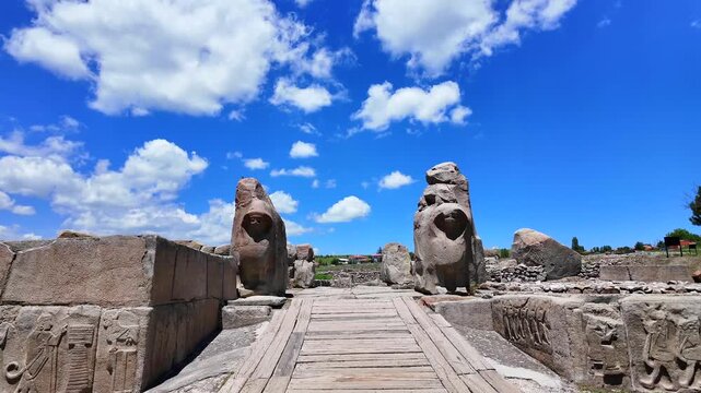 Two massive stone sphinx statues flank the entrance gate of the ancient Hittite site Alacah&ouml;y&uuml;k beneath a blue sky.