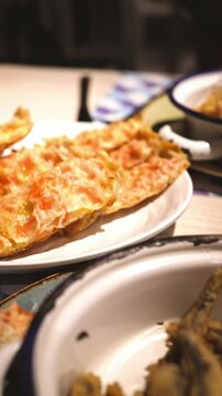 Closeup of crispy fried boquerones with pan con tomate in background, spanish tapas