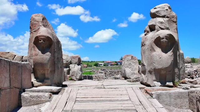Two massive stone sphinx statues flank the entrance gate of the ancient Hittite site Alacah&ouml;y&uuml;k beneath a blue sky.