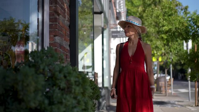 A senior woman enjoys window shopping on the main street in St Helena, Napa, California during sunrise.
