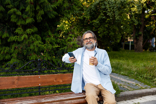 Senior man relaxing on park bench using phone
