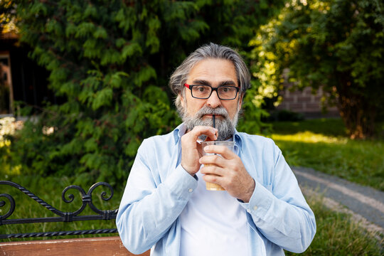 Bearded man drinking iced coffee outdoors