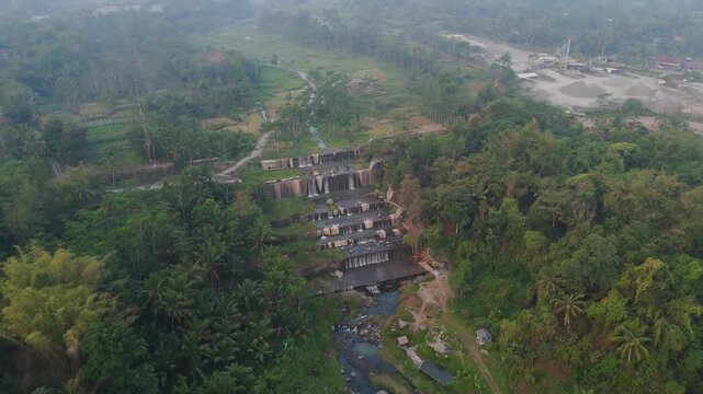 Aerial view of the tiered waterfall Grojogan Watu Purbo surrounded by lush tropical vegetation and trees in Tempel, Yogyakarta, Indonesia.